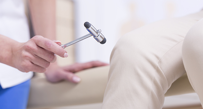 Neurólogo examinando reflejos de paciente.